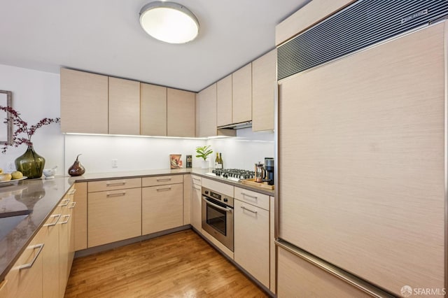 301 Mission St Unit 6J, San Francisco, CA 94105 - kitchen with appliances with stainless steel finishes, light wood finished floors, under cabinet range hood, cream cabinetry, and light brown cabinets