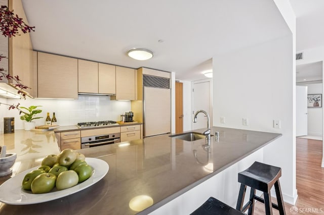 301 Mission St Unit 6J, San Francisco, CA 94105 - kitchen featuring stainless steel appliances, a peninsula, a breakfast bar area, light brown cabinets, and light wood-type flooring