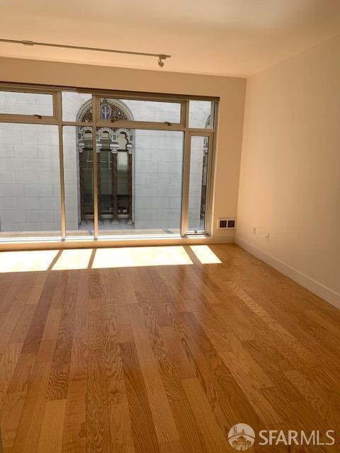 unfurnished room featuring wood finished floors, visible vents, and baseboards