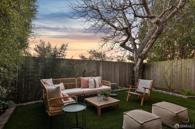 patio terrace at dusk featuring outdoor lounge area and a lawn