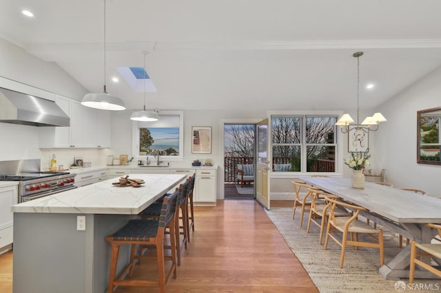 kitchen with wall chimney exhaust hood, a center island, pendant lighting, and sink