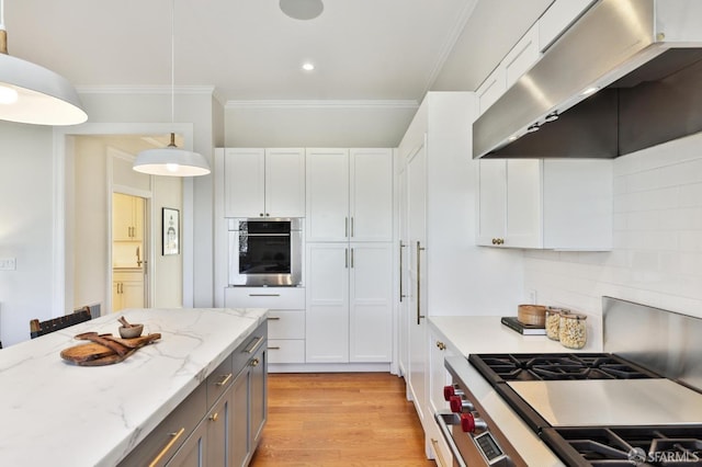 kitchen featuring crown molding, decorative light fixtures, tasteful backsplash, white cabinetry, and stainless steel appliances