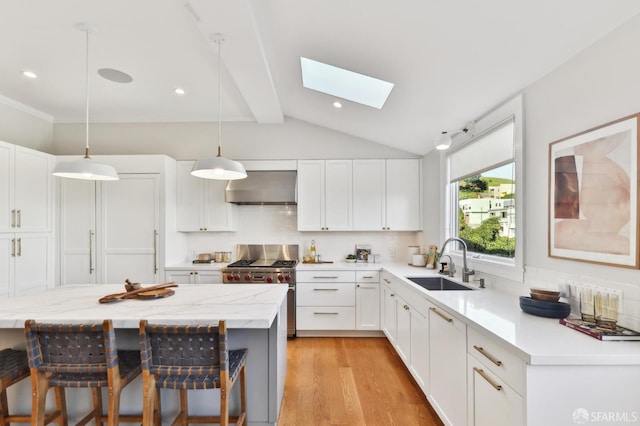 kitchen with pendant lighting, wall chimney exhaust hood, sink, backsplash, and white cabinets