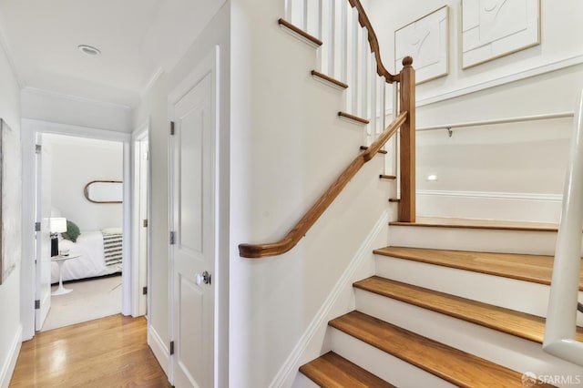 stairway featuring crown molding and hardwood / wood-style flooring