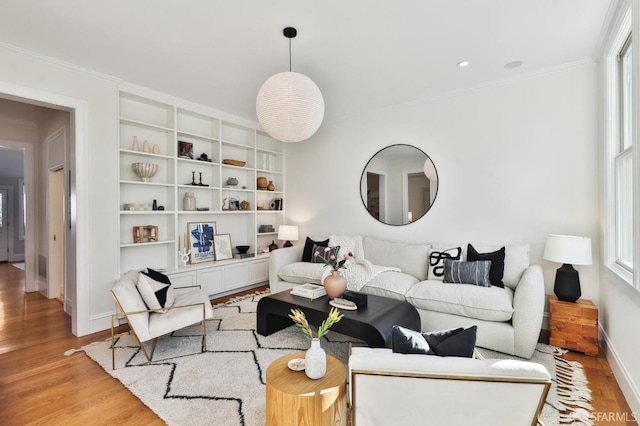 living room with light wood-type flooring, ornamental molding, and built in features