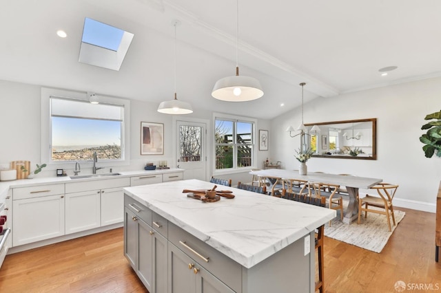 kitchen featuring a center island, a wealth of natural light, vaulted ceiling with skylight, sink, and pendant lighting