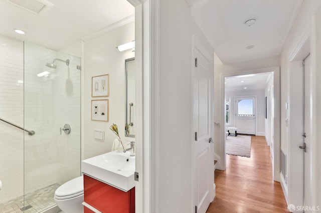 bathroom with wood-type flooring, crown molding, walk in shower, and vanity