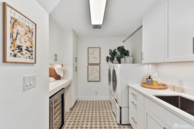 laundry area with sink, beverage cooler, cabinets, and independent washer and dryer