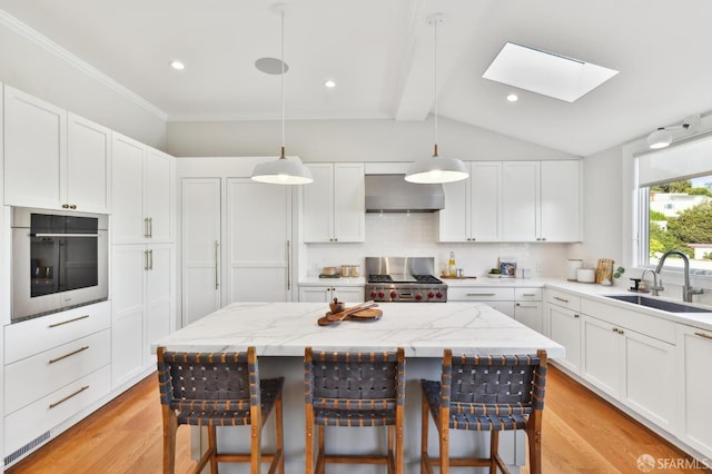 kitchen with stainless steel oven, range, sink, decorative light fixtures, and a kitchen island