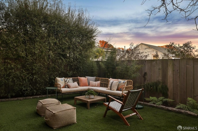 patio terrace at dusk featuring an outdoor living space and a lawn