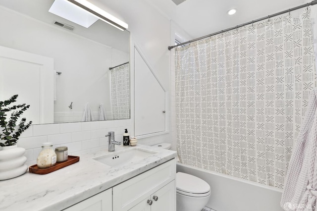 full bathroom with toilet, a skylight, shower / bath combo, vanity, and backsplash