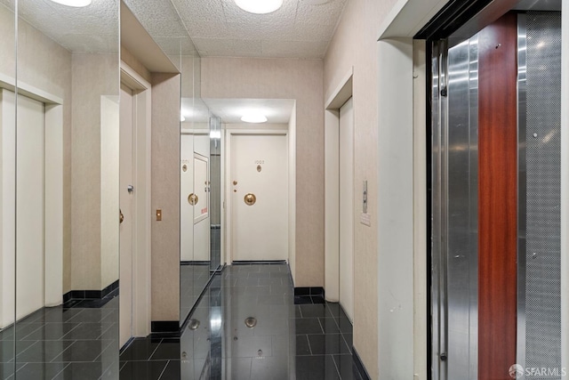 hall with elevator and dark tile patterned flooring