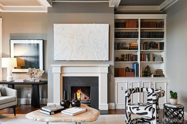 living area featuring a lit fireplace, ornamental molding, and wood finished floors