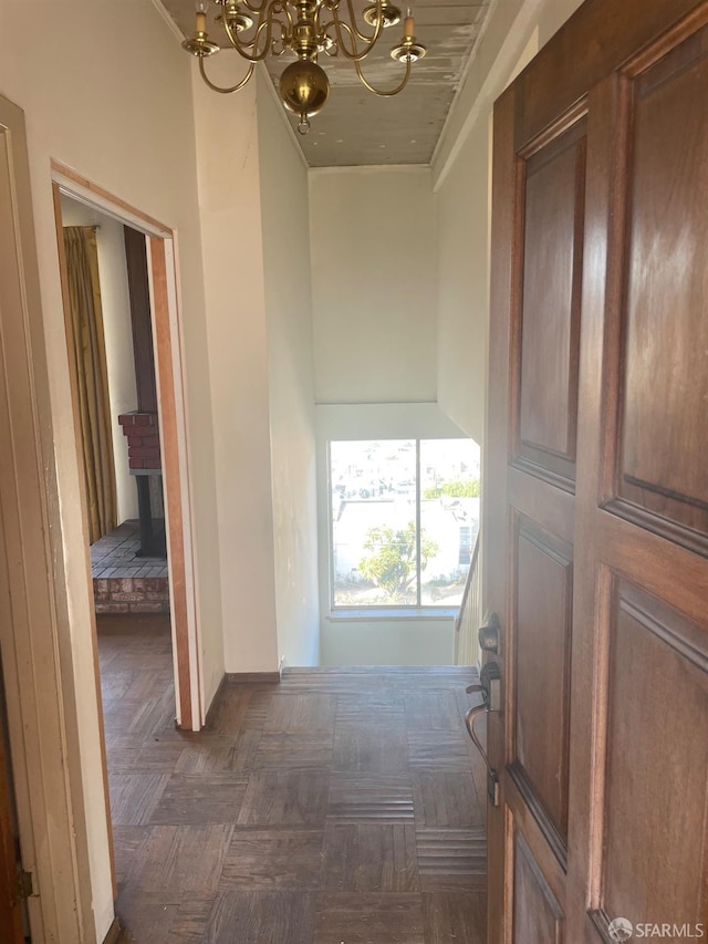 hall with dark parquet flooring and a notable chandelier