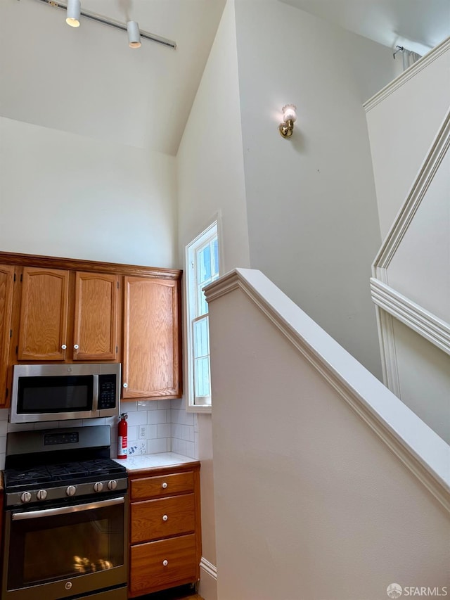 3543-3545 24th St, San Francisco, CA 94110 - kitchen with appliances with stainless steel finishes, tasteful backsplash, brown cabinetry, light countertops, and high vaulted ceiling