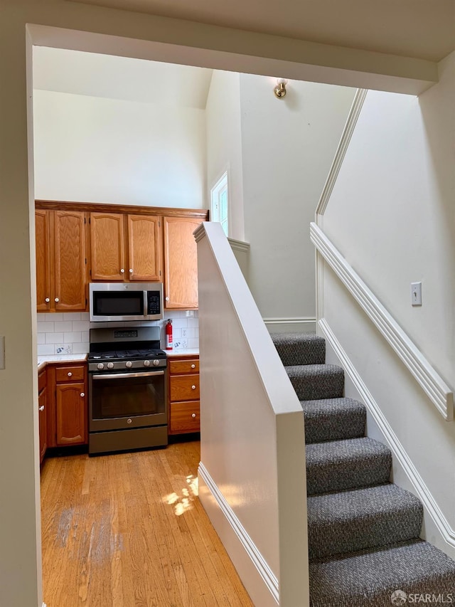 3543-3545 24th St, San Francisco, CA 94110 - kitchen featuring appliances with stainless steel finishes, light wood finished floors, tasteful backsplash, and light countertops
