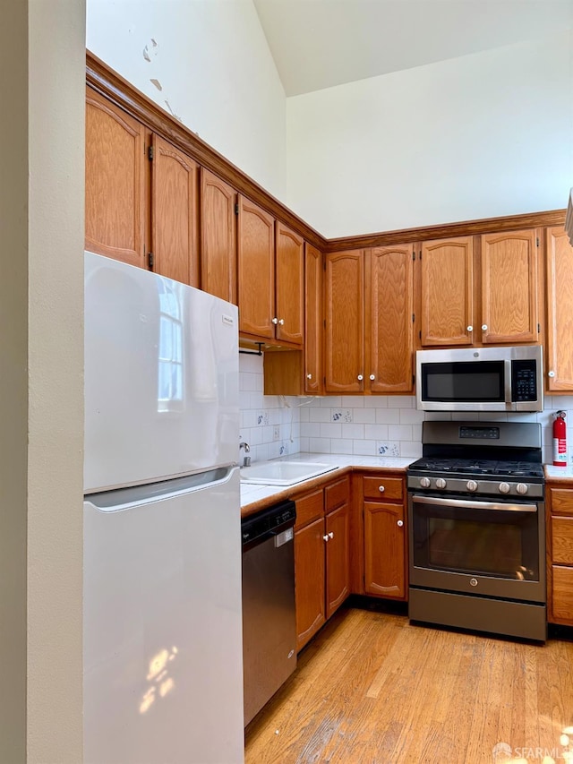 3543-3545 24th St, San Francisco, CA 94110 - kitchen featuring stainless steel appliances, a sink, light countertops, light wood-type flooring, and decorative backsplash
