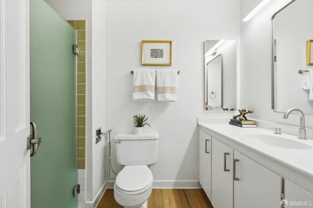 full bathroom with toilet, a stall shower, vanity, wood finished floors, and baseboards