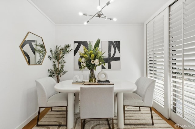 dining space featuring an inviting chandelier, baseboards, ornamental molding, and wood finished floors