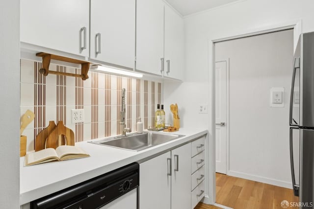 kitchen featuring freestanding refrigerator, a sink, white dishwasher, light countertops, and backsplash