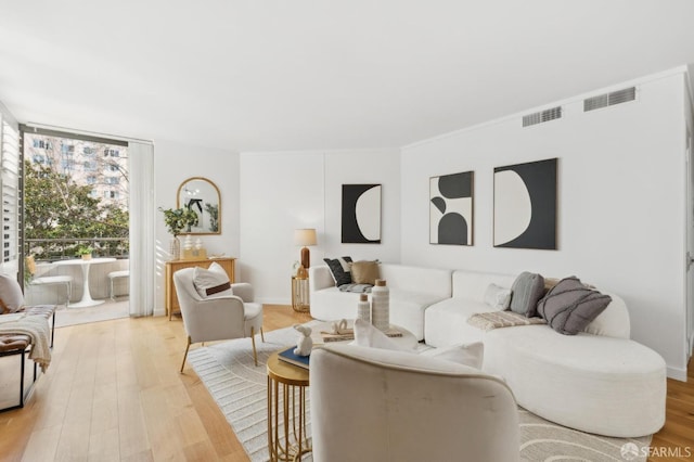 living room with a wall of windows, visible vents, and light wood-style floors