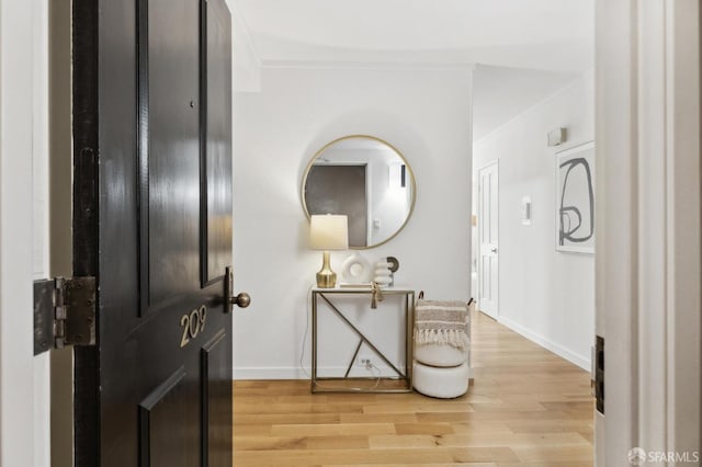 interior space with light wood-style flooring, baseboards, and ornamental molding