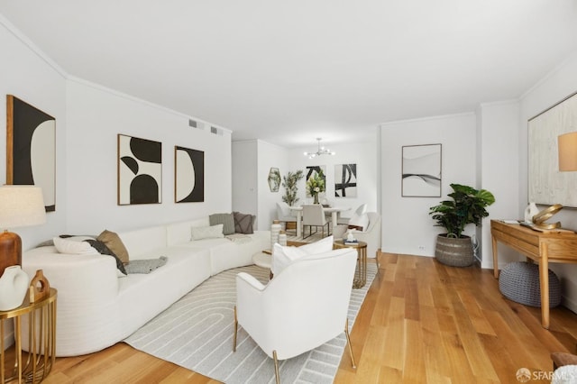 living room featuring light wood-type flooring, crown molding, and a notable chandelier