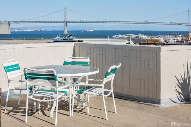 balcony with outdoor dining space and a water view