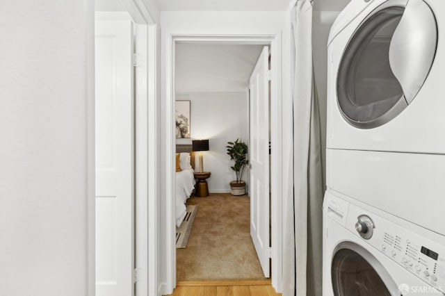 laundry area with light carpet and stacked washer and clothes dryer