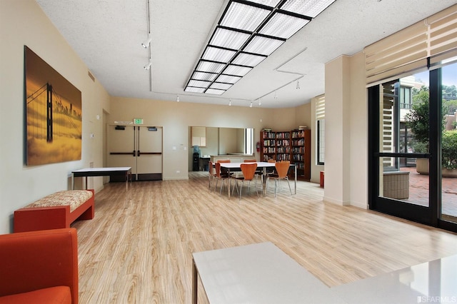 dining space with baseboards, a textured ceiling, track lighting, and wood finished floors