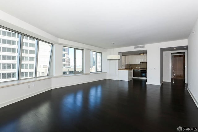 unfurnished living room featuring dark wood-style floors, visible vents, and baseboards