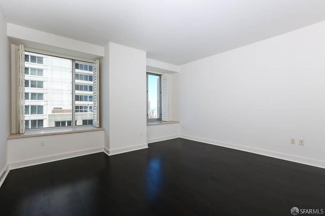 spare room with dark wood-type flooring and baseboards