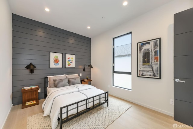 bedroom with an accent wall, recessed lighting, light wood-style flooring, and baseboards