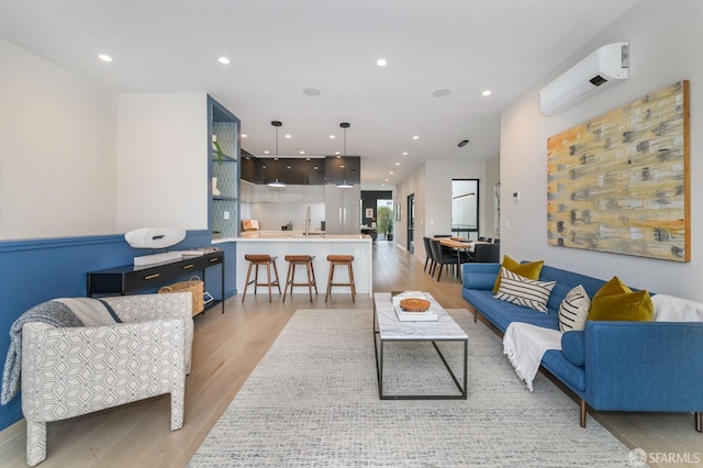 living area with light wood finished floors, a wall mounted air conditioner, and recessed lighting