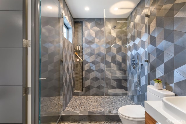 bathroom featuring tile walls, a shower stall, vanity, and toilet