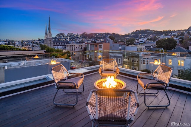 deck at dusk featuring an outdoor fire pit and a city view