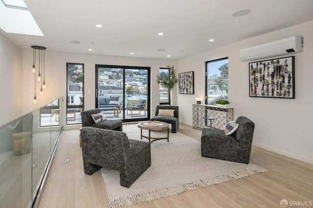 living room with a skylight, an AC wall unit, light wood finished floors, and recessed lighting