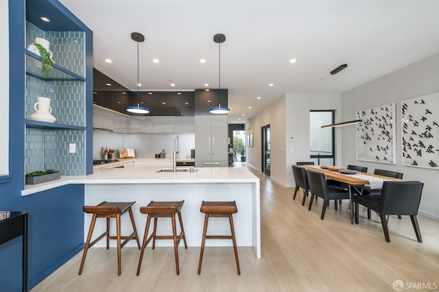 kitchen featuring open shelves, light countertops, a sink, modern cabinets, and a peninsula