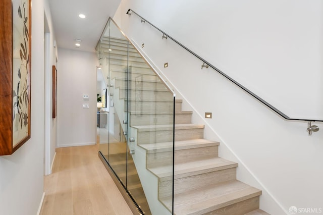 stairs with baseboards, wood finished floors, and recessed lighting