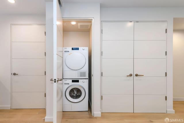 washroom with laundry area, light wood-style flooring, visible vents, and stacked washer and clothes dryer