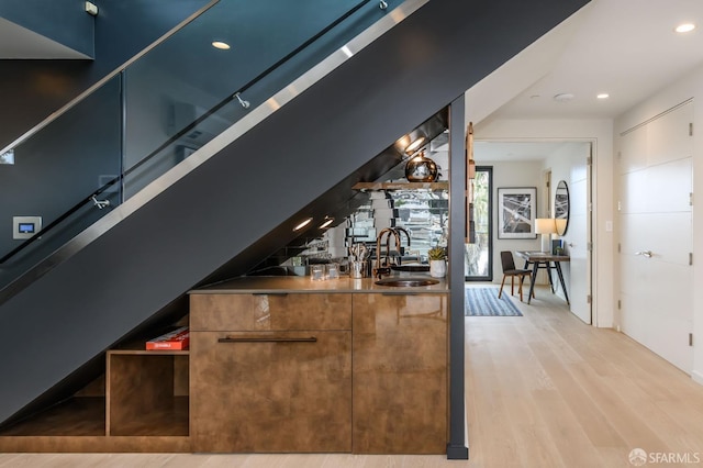 bar featuring light wood-style floors, recessed lighting, and a sink