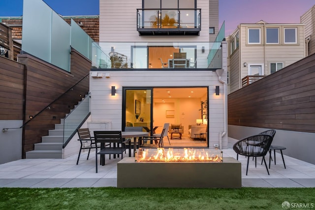 back of property at dusk with a fire pit, a patio, and stairs