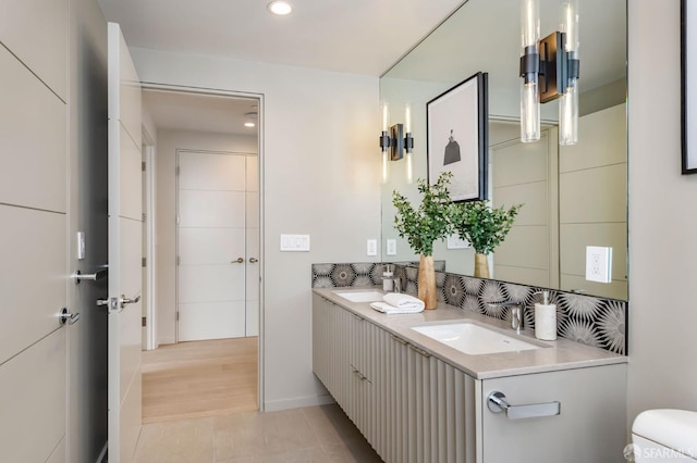 bathroom with double vanity, toilet, a sink, and recessed lighting