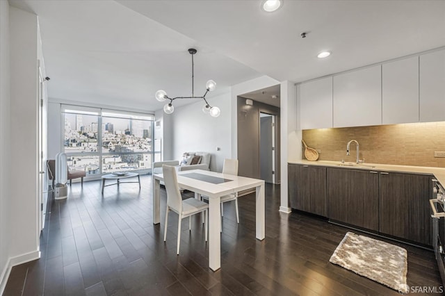 dining room featuring a wall of windows, dark hardwood / wood-style floors, sink, and a notable chandelier