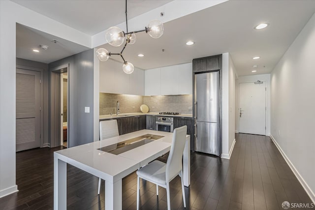 kitchen with appliances with stainless steel finishes, tasteful backsplash, hanging light fixtures, white cabinets, and sink