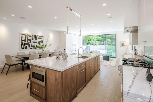 3537 23rd St Unit A, San Francisco, CA 94110 - kitchen with light stone countertops, a sink, stainless steel appliances, light wood-type flooring, and a spacious island