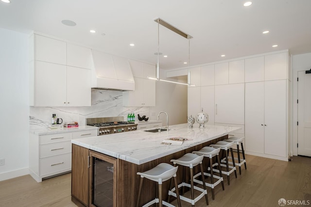 3537 23rd St Unit A, San Francisco, CA 94110 - kitchen with a sink, decorative backsplash, wine cooler, light wood-type flooring, and premium range hood