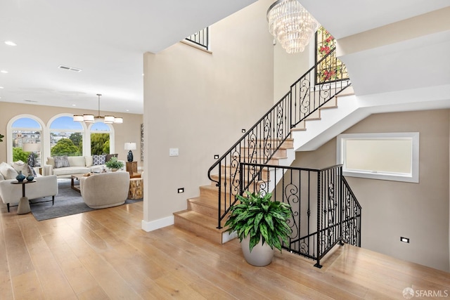 stairs with a chandelier and hardwood / wood-style flooring