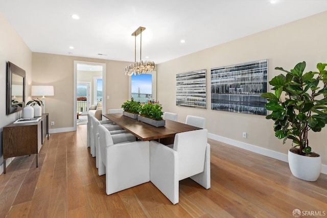 dining space with light hardwood / wood-style flooring and a chandelier