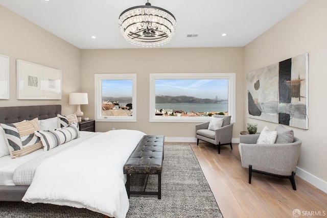 bedroom with light wood-type flooring and an inviting chandelier